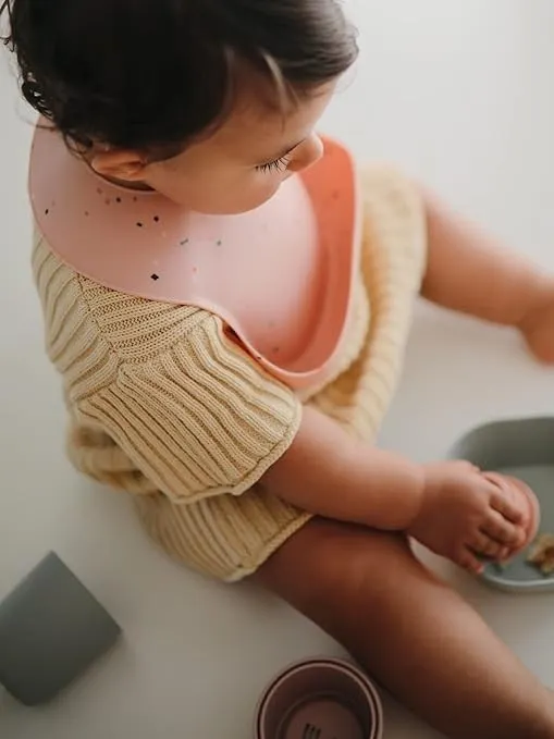 Mushie - śliniak silikonowy z kieszonką Powder Pink Confetti